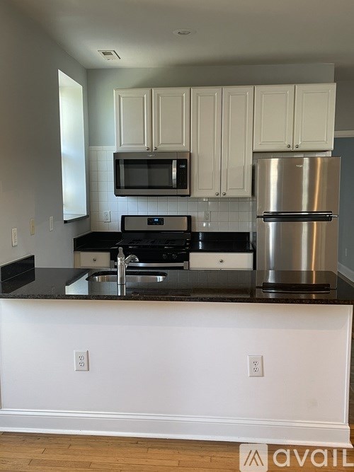 A kitchen with white cabinets and a black countertop.