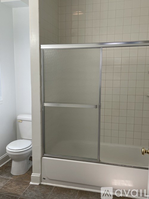A white toilet sits next to a glass shower door in a bathroom.