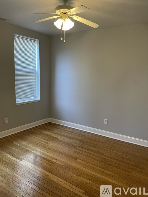 A room with a ceiling fan and wooden flooring.