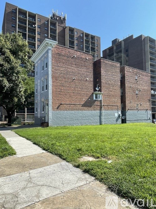 A white building with a brick wall in front of a grassy area.
