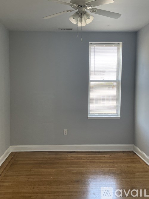 A room with a ceiling fan and a window with blinds.