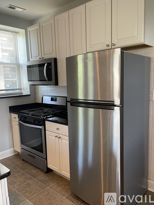 A kitchen with a stainless steel refrigerator, microwave, oven, and black stove.