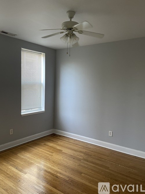 A room with a ceiling fan and wooden flooring.