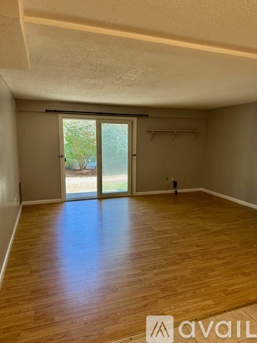 A room with wooden flooring and a sliding glass door leading outside.