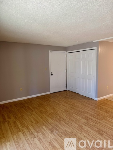 A room with a white door and wooden flooring.