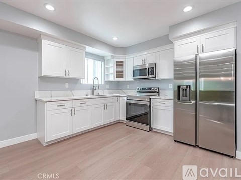 A modern kitchen with white cabinets and stainless steel appliances.