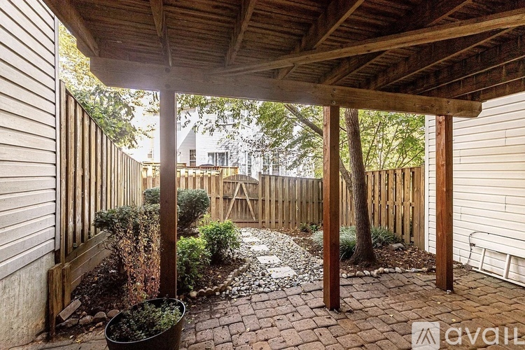 A patio with a wooden pergola and a brick walkway.