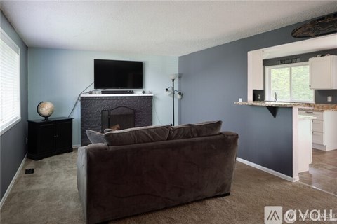 A living room with a brown couch and a fireplace.