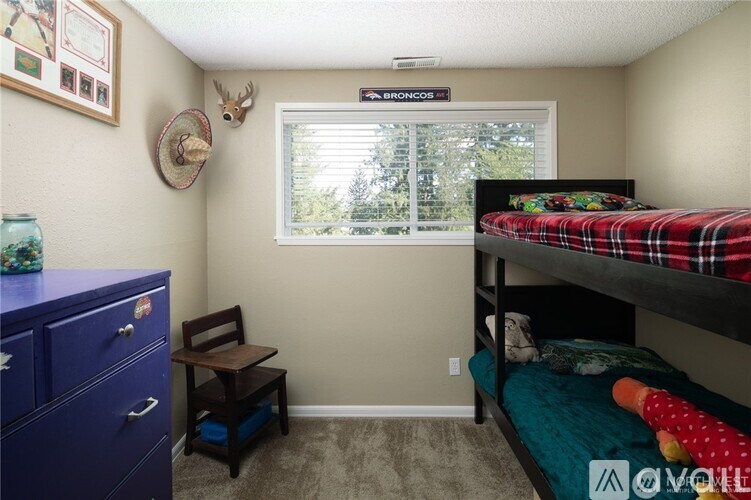A bedroom with a bunk bed and a window with blinds.