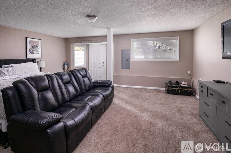 A black leather sofa in a room with a bed and a television.