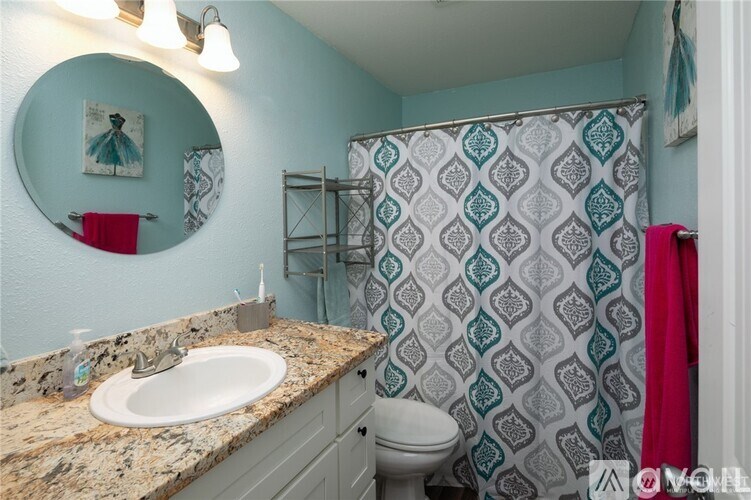 A bathroom with a patterned shower curtain and a round mirror.