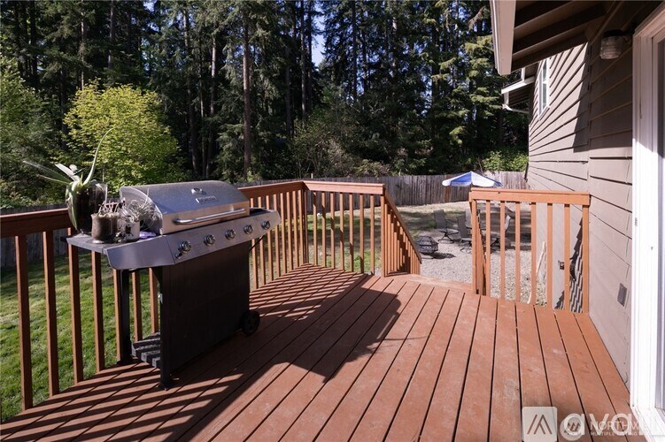 A BBQ grill is on a wooden deck with a forest in the background.