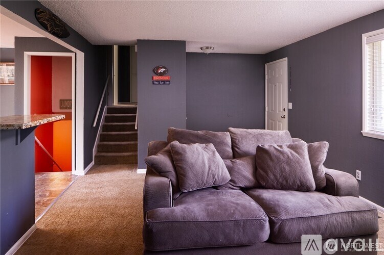 A living room with a grey couch and a staircase.