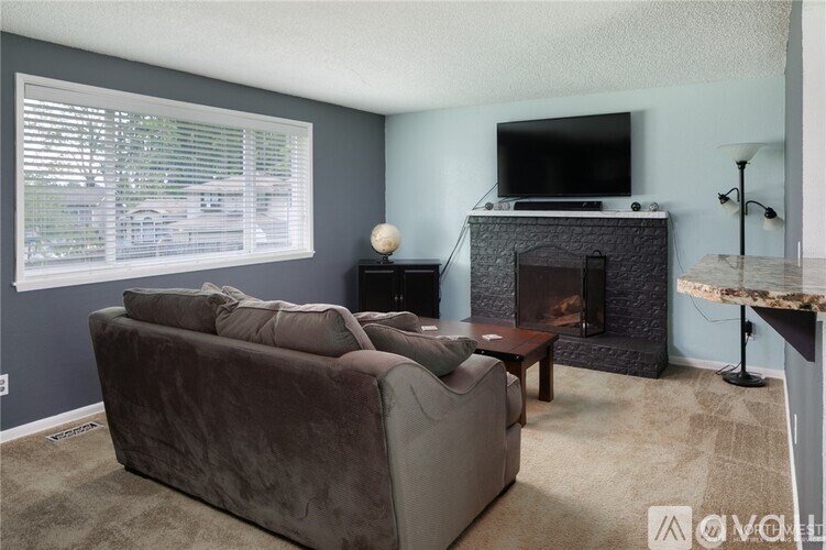 A living room with a grey couch, a fireplace, and a television.