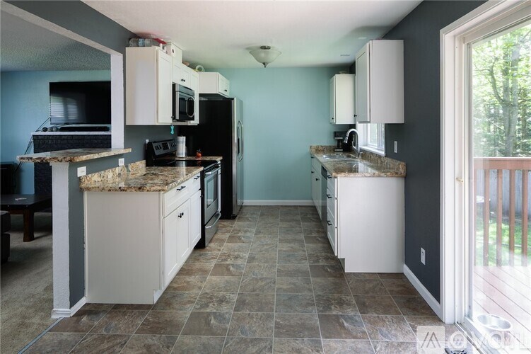 A kitchen with a black fridge and white cabinets.