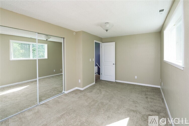 A room with a carpeted floor, a door, and a window.
