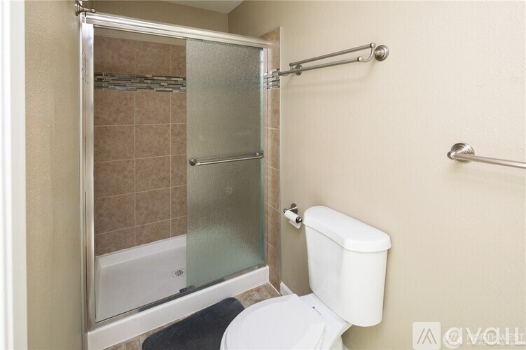 A white toilet sits next to a glass shower door in a bathroom.