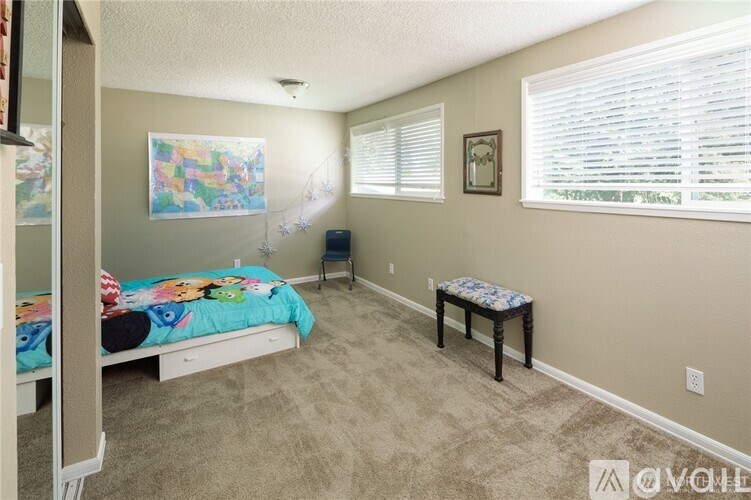 A bedroom with a bed, a chair, and a window with blinds.