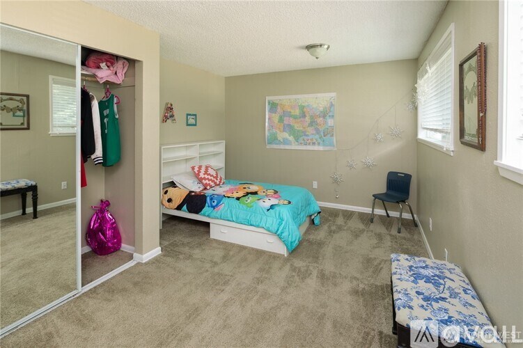 A bedroom with a bed, a chair, and a closet with clothes hanging.