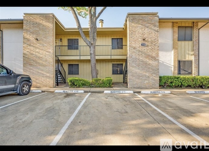 A parking lot in front of a two-story apartment building.