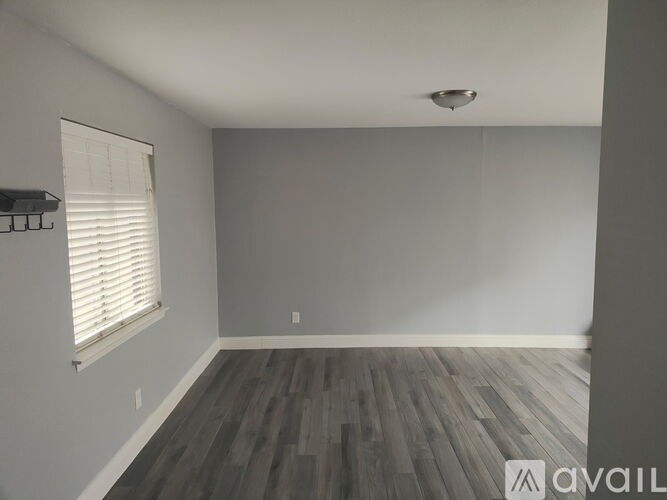 A room with wooden flooring and a window with blinds.