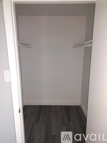 A white closet with a wooden floor and two shelves.