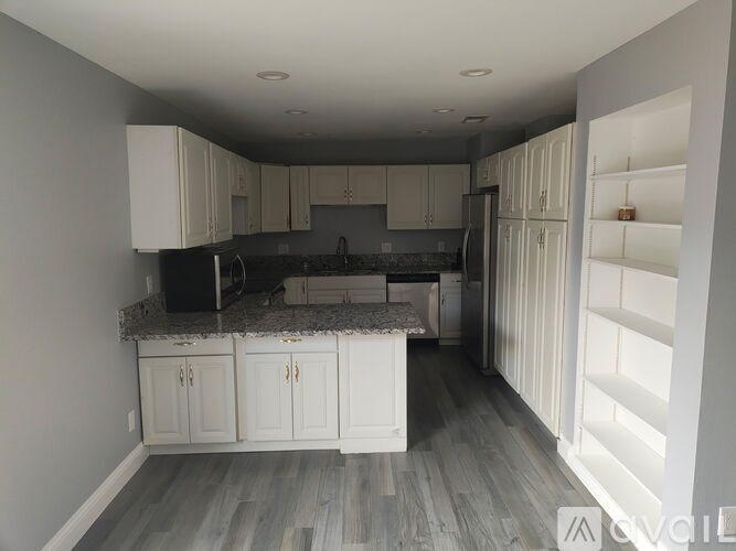 A kitchen with white cabinets and a black countertop.