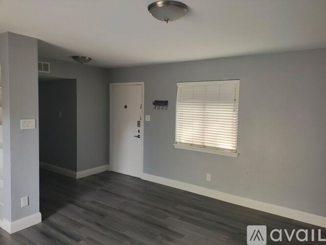 A room with a door and a window with blinds.