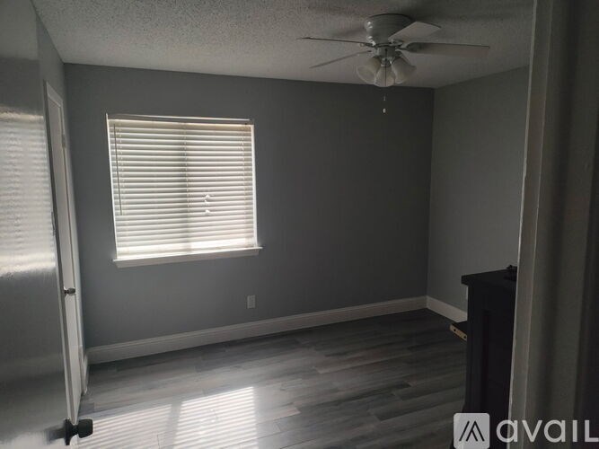 A room with a ceiling fan and a window with blinds.