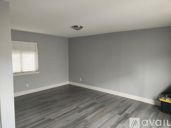 A room with grey walls and wooden flooring is available for rent.