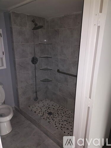 A bathroom with a toilet, a shower with a glass door, and a tiled floor.