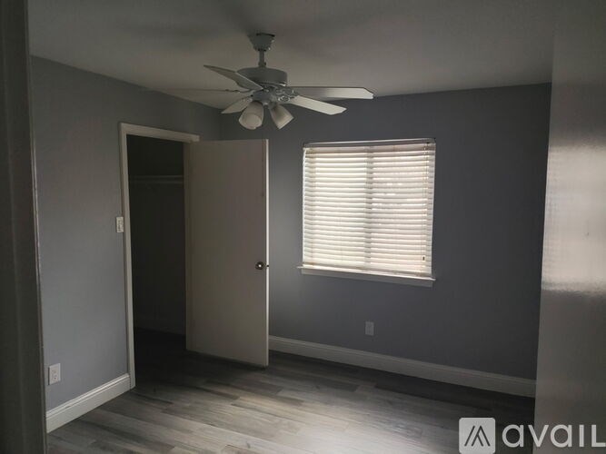 A room with a ceiling fan and a window with blinds.