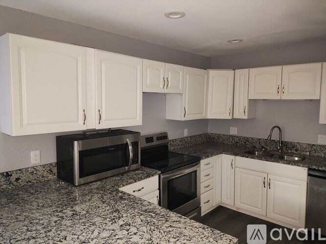 A kitchen with granite countertops and white cabinets.