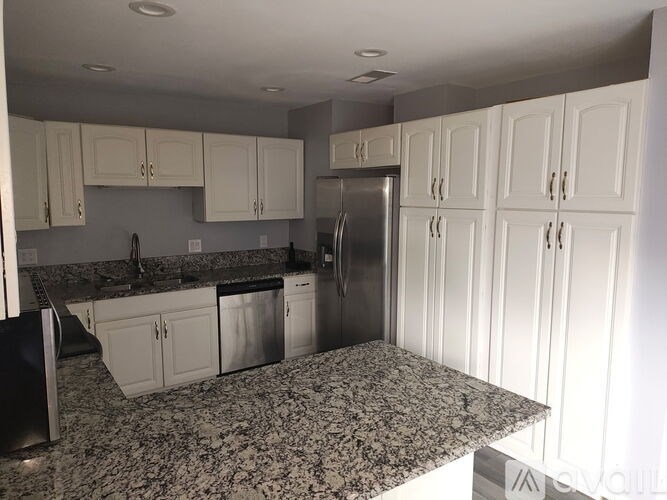 A kitchen with granite countertops and white cabinets.