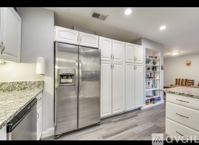 A modern kitchen with a stainless steel refrigerator and white cabinets.