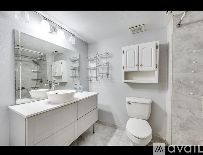 A bathroom with a white toilet, sink, and cabinet.