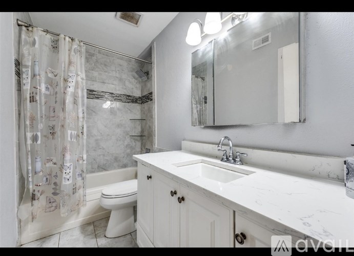 A bathroom with a white toilet, sink, and shower curtain.