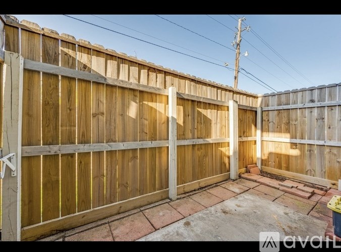 A wooden fence with a gate in the middle and a brick pathway leading to it.