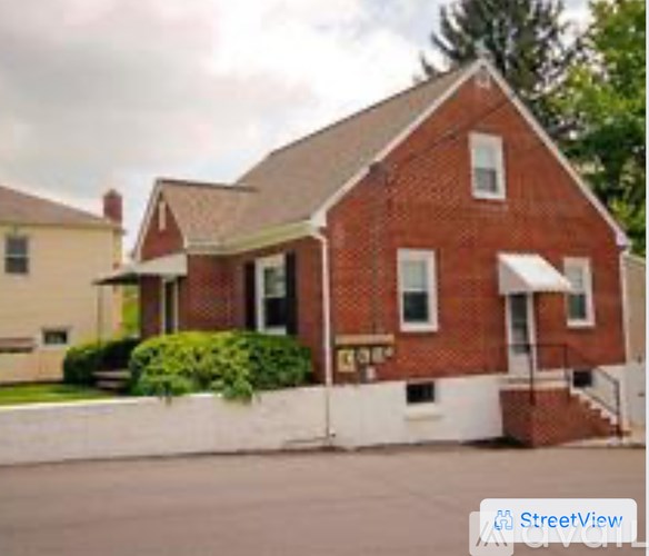 A red brick house with a white porch.