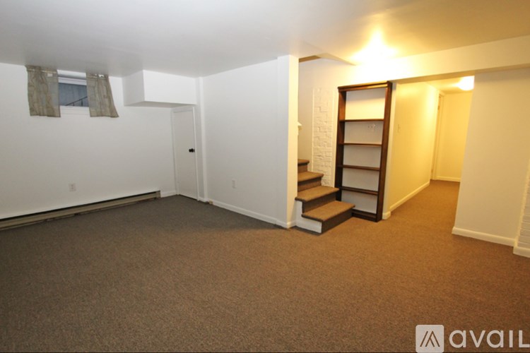 A room with a carpeted floor and a staircase leading to a second floor.