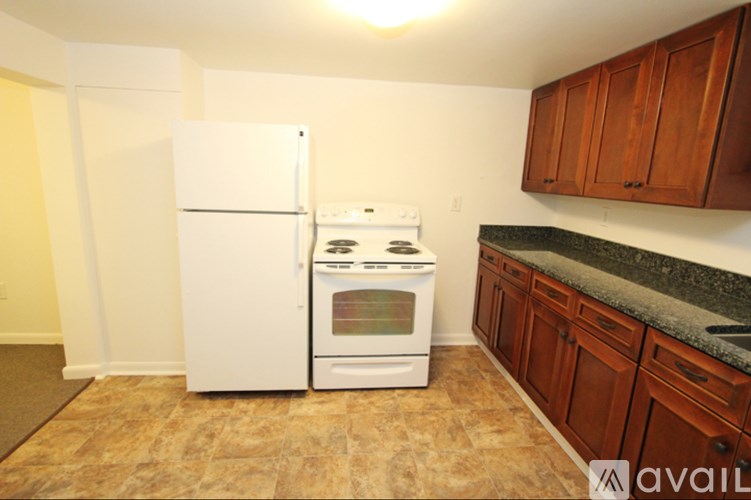 A kitchen with a white fridge and stove, wooden cabinets and a tiled floor.