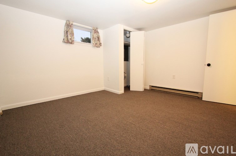 A room with carpeted floor and a window with curtains.