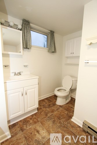 A small bathroom with a toilet, sink, and brown tiled floor.