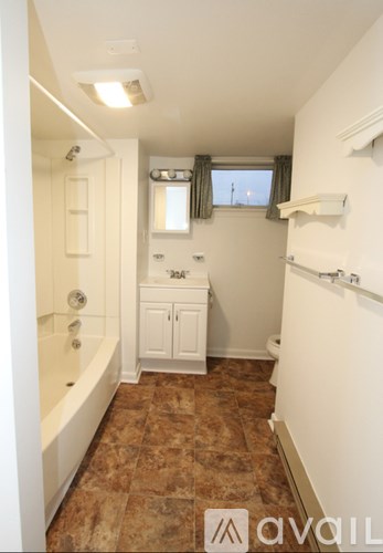 A bathroom with brown tiles and white fixtures.