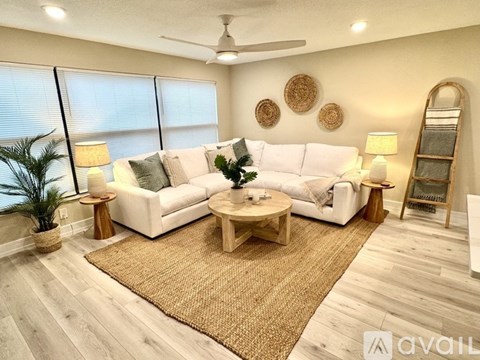 A living room with a white couch, a wooden coffee table, and a rug on the floor.