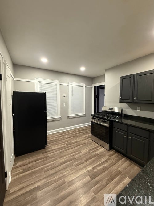 A kitchen with black cabinets and a black refrigerator.