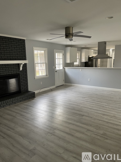 A spacious living room with a fireplace and a ceiling fan.