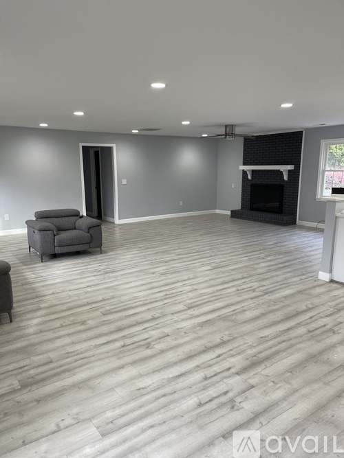 A spacious living room with a grey sofa and a fireplace.