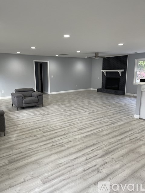 A spacious living room with a grey sofa and a fireplace.