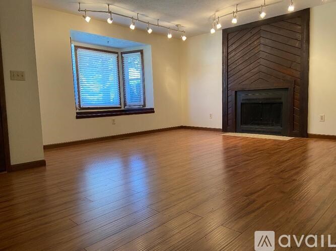 A room with wooden flooring and a fireplace.